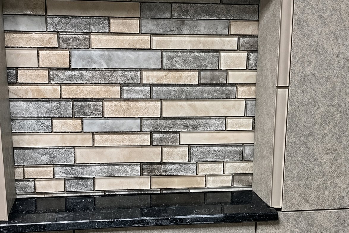 Tiled shower niche lined with a mosaic of glass and stone tile