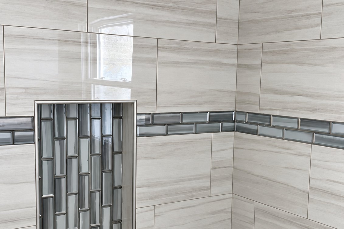 Tub surround in white and gray wood-grain porcelain tile with a glass tile niche