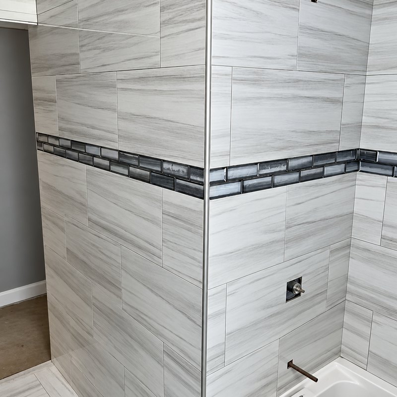 Corner of a tub surround tiled in white and gray wood-grain porcelain