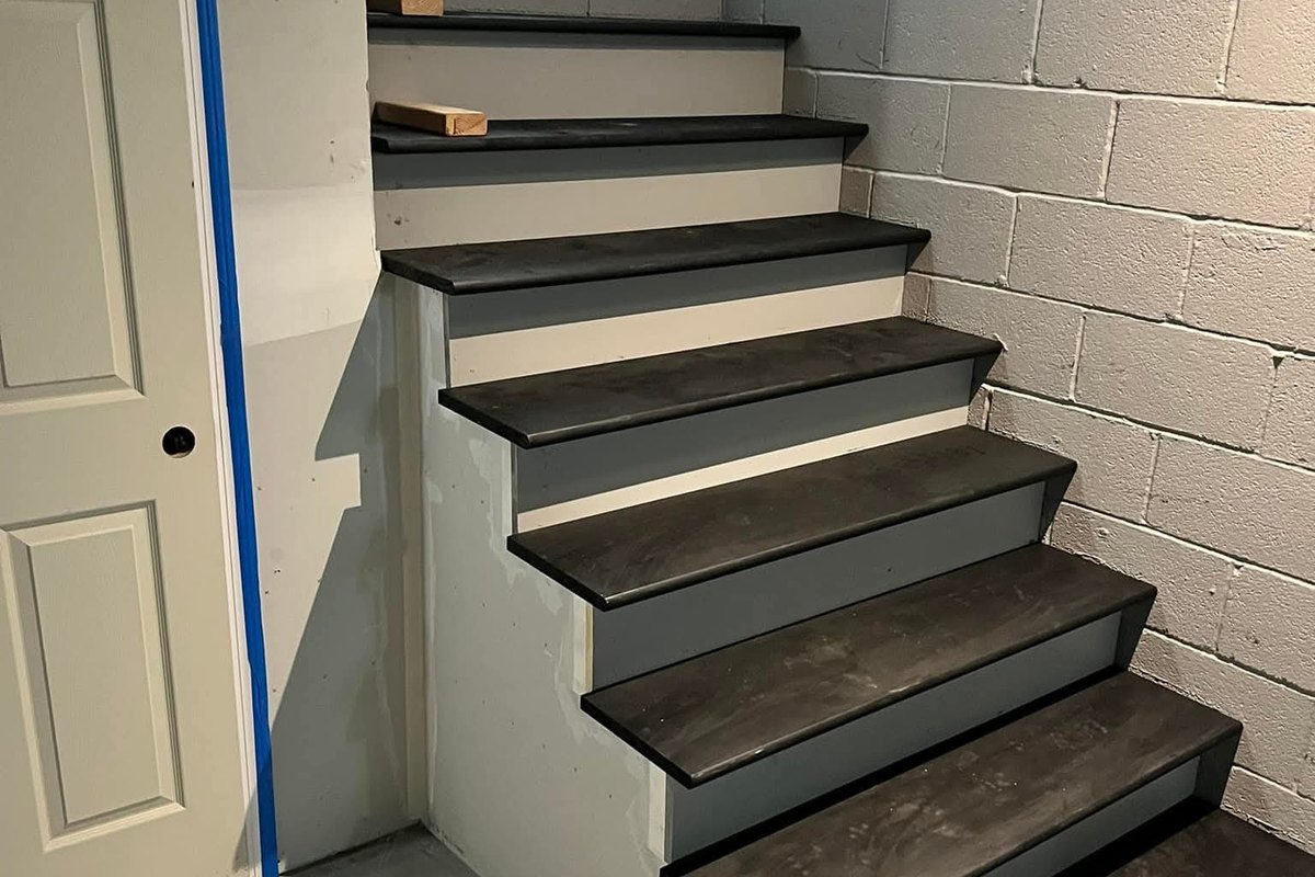 Basement stairs with white risers and dark gray plank treads curving around a corner