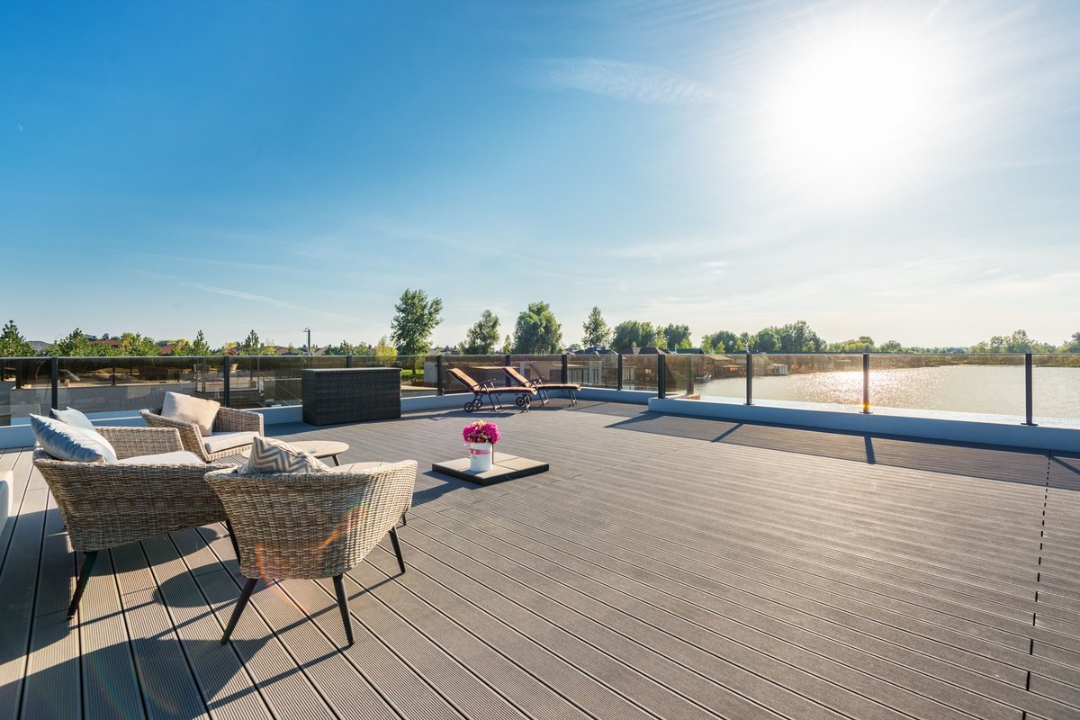 Wide gray grooved composite deck with glass panel railings beside open water