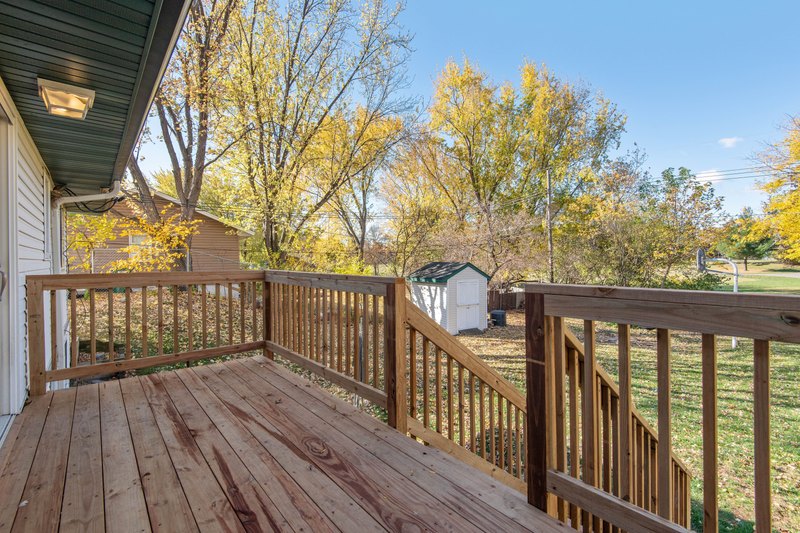 New wood deck with railings and stairs over a green backyard with scattered autumn leaves