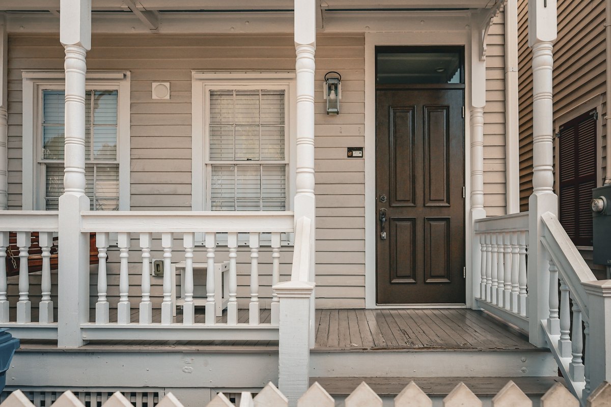 Dark brown wood front door with a transom on a white-railed porch