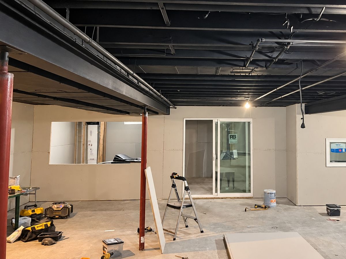 Open basement with drywall hung on the walls, a window cut into one wall, a sliding glass door