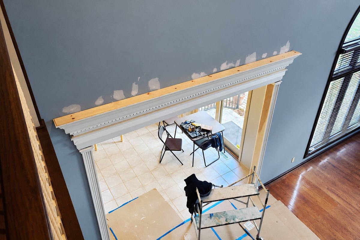 Dentil header being built over a wide opening below a wall with fresh drywall patches
