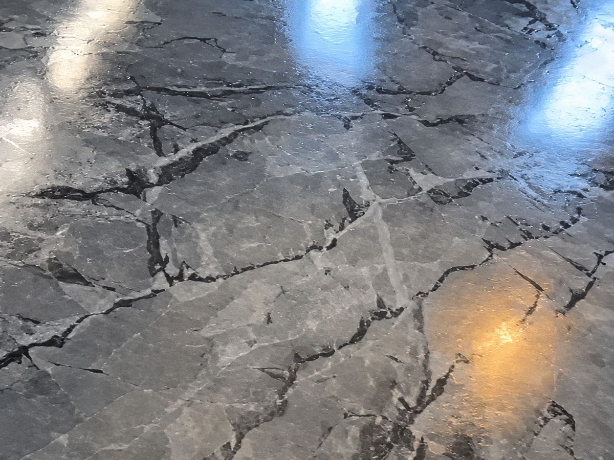 Close-up of a glossy gray marble-look epoxy floor with black and white veining