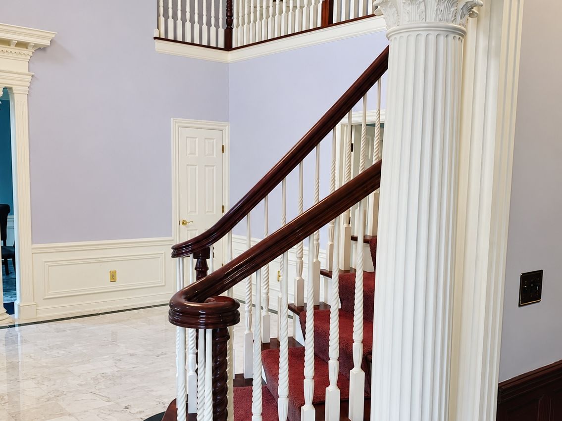 Two-story foyer: staircase with a curved mahogany handrail, white twisted and turned balusters