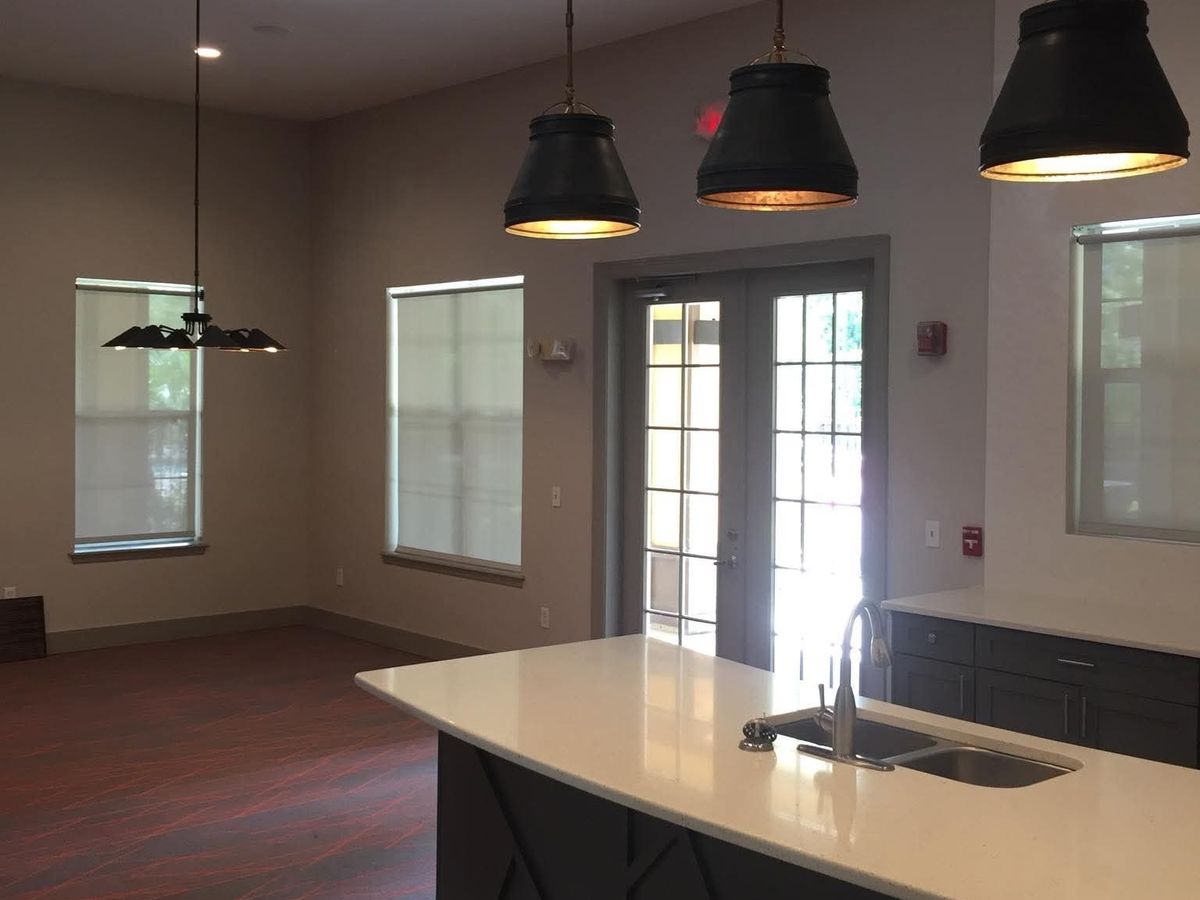 Open kitchenette with a dark angular-trim island, white countertop, three black pendant lights, and gray herringbone tile