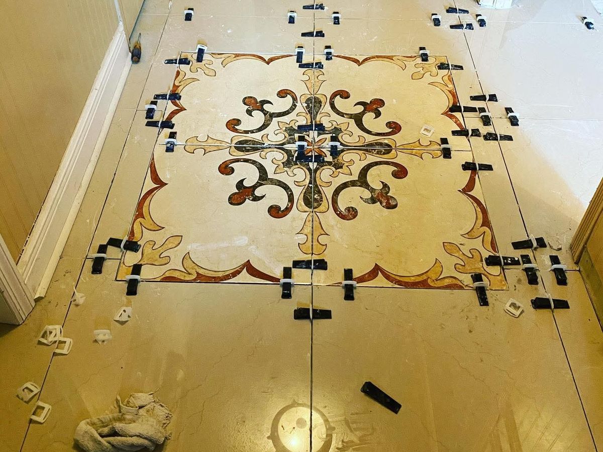 Hallway floor of large polished cream porcelain tiles around a decorative inlaid red, gold and brown medallion