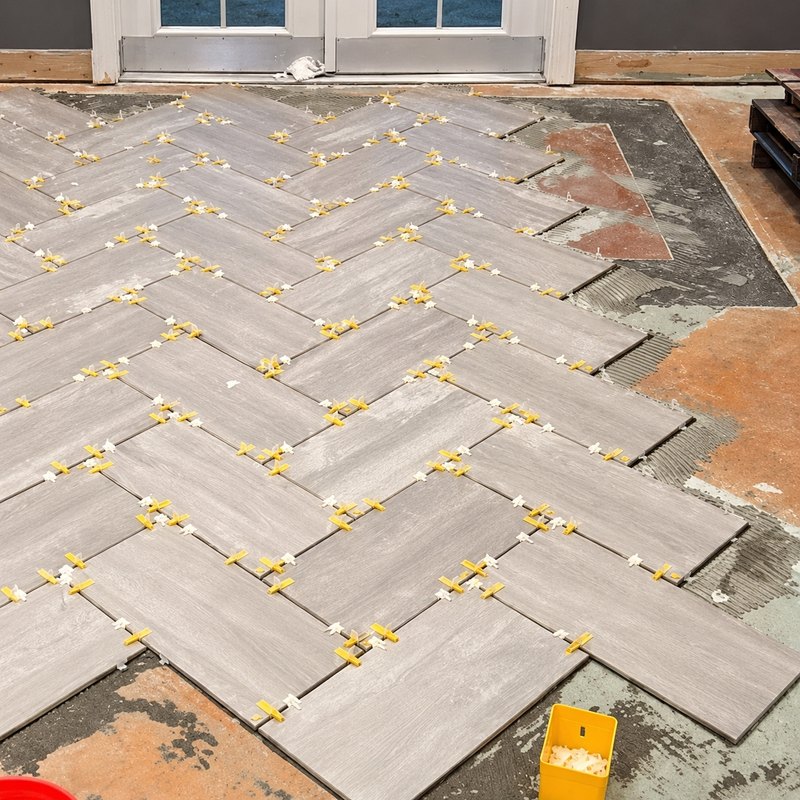Gray wood-look porcelain plank tile laid in a herringbone pattern