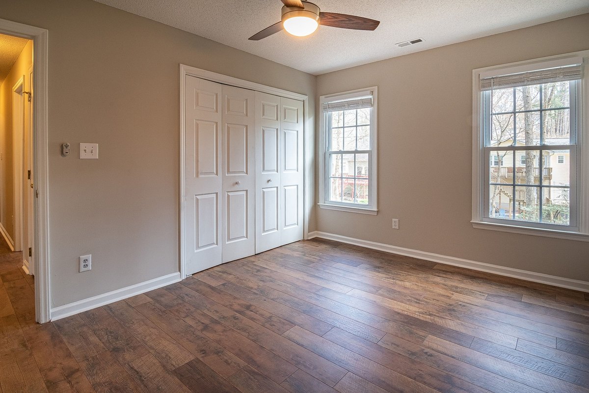 Empty bedroom with a dark brown wood-look plank floor and white closet doors
