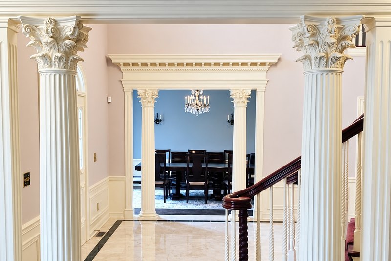 Front hall with cream fluted Corinthian columns and white raised-panel wainscoting