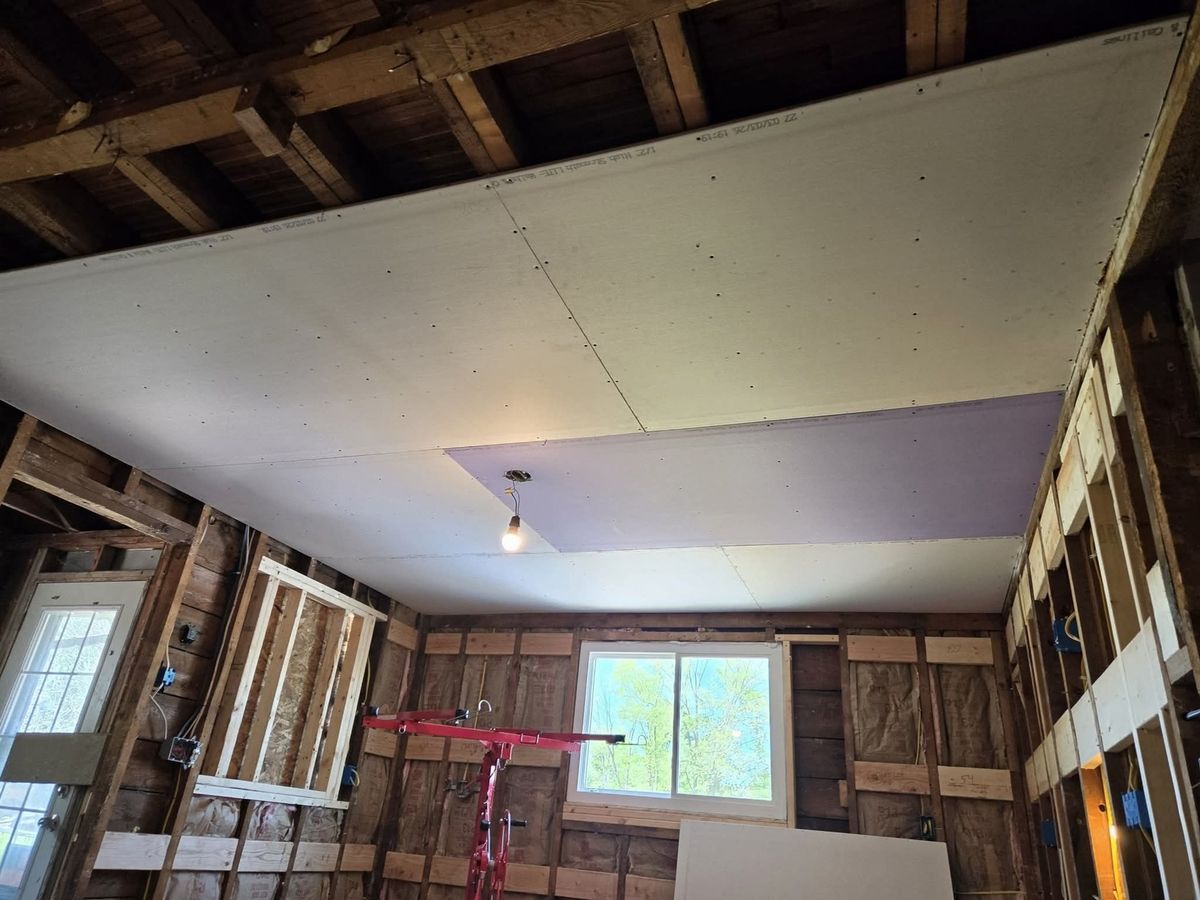 Gutted room with exposed wall studs, pink insulation and old planks