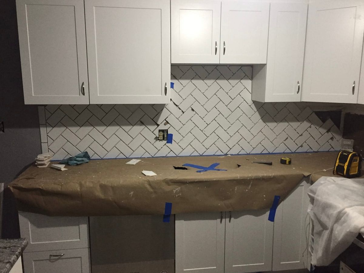 Kitchen under construction: white shaker upper and base cabinets with a white subway tile backsplash