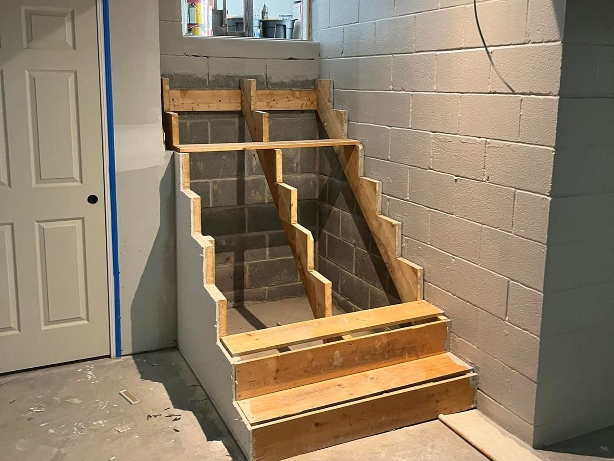 Basement stairs framed in lumber with a landing and the first two steps built against a block wall