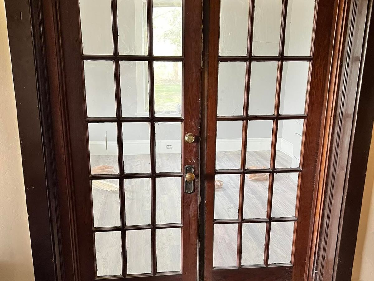 Pair of dark wood French doors with fifteen glass panes each in a dark wood frame, a brass handle
