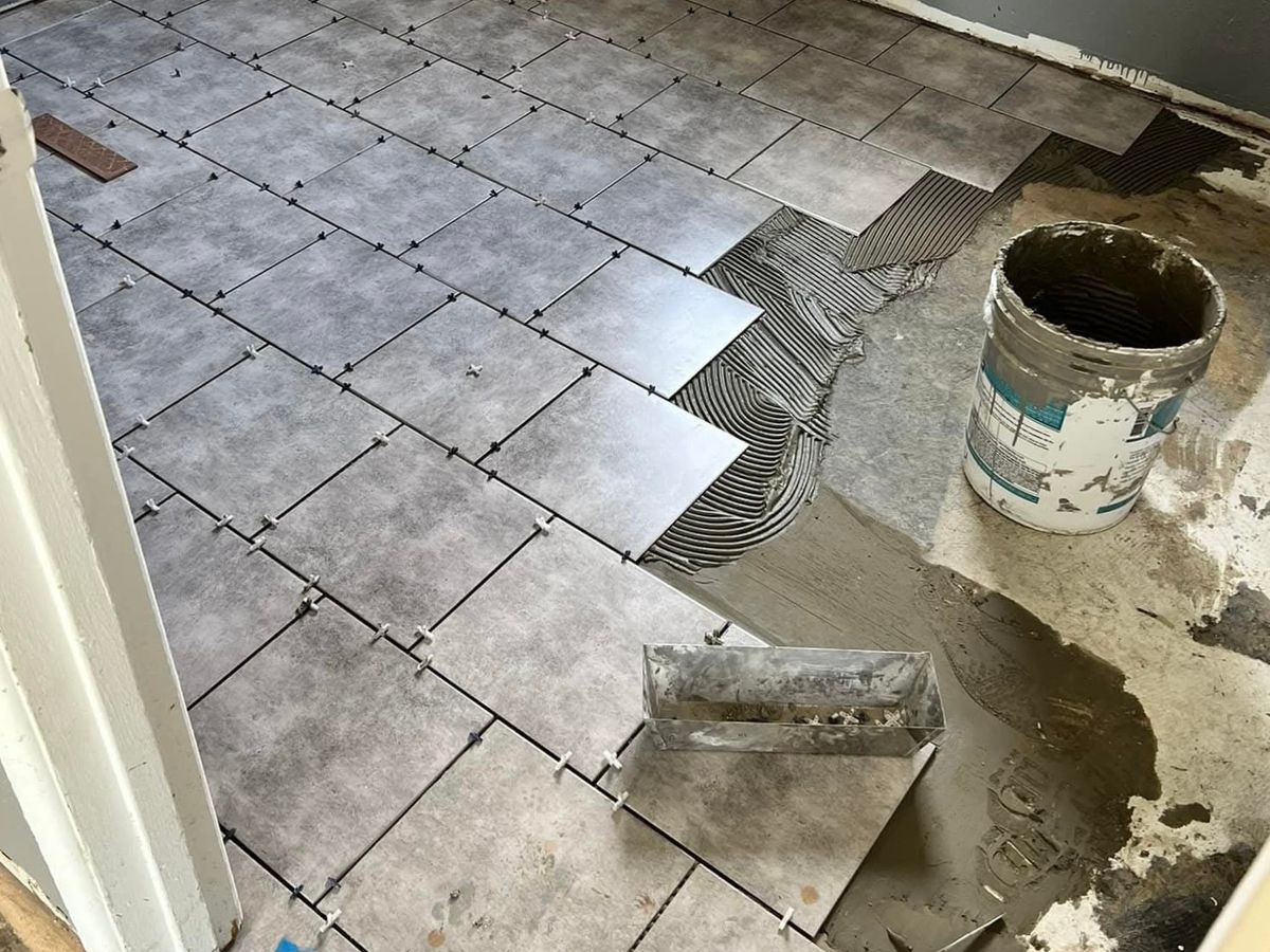 Large square gray porcelain floor tiles set with spacers on a room floor