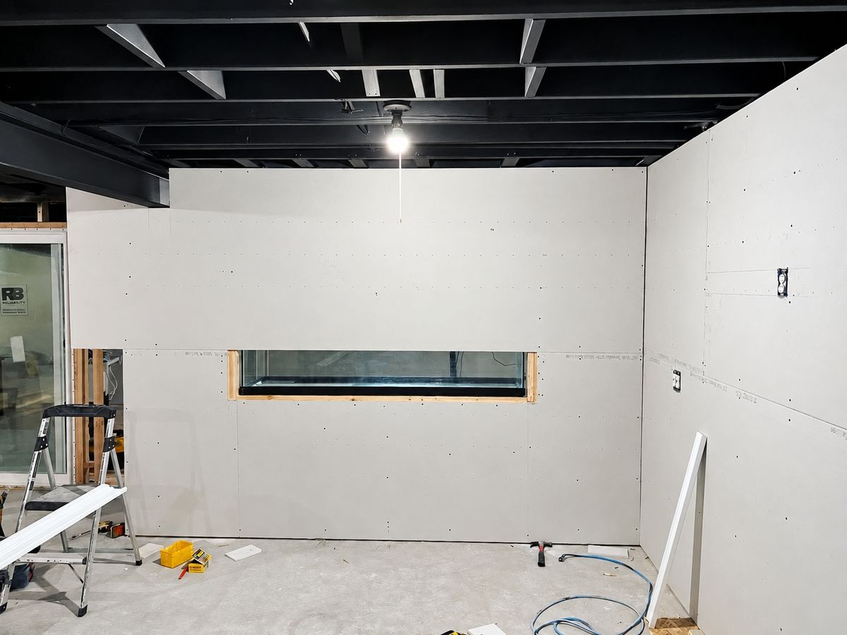 Basement with a new drywall wall and a long rectangular window cut into it
