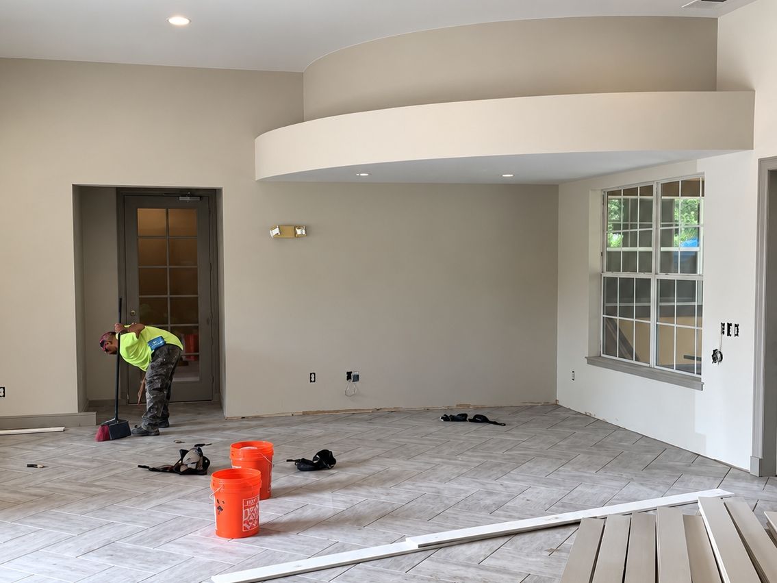 Large open room with herringbone gray porcelain plank tile partly laid
