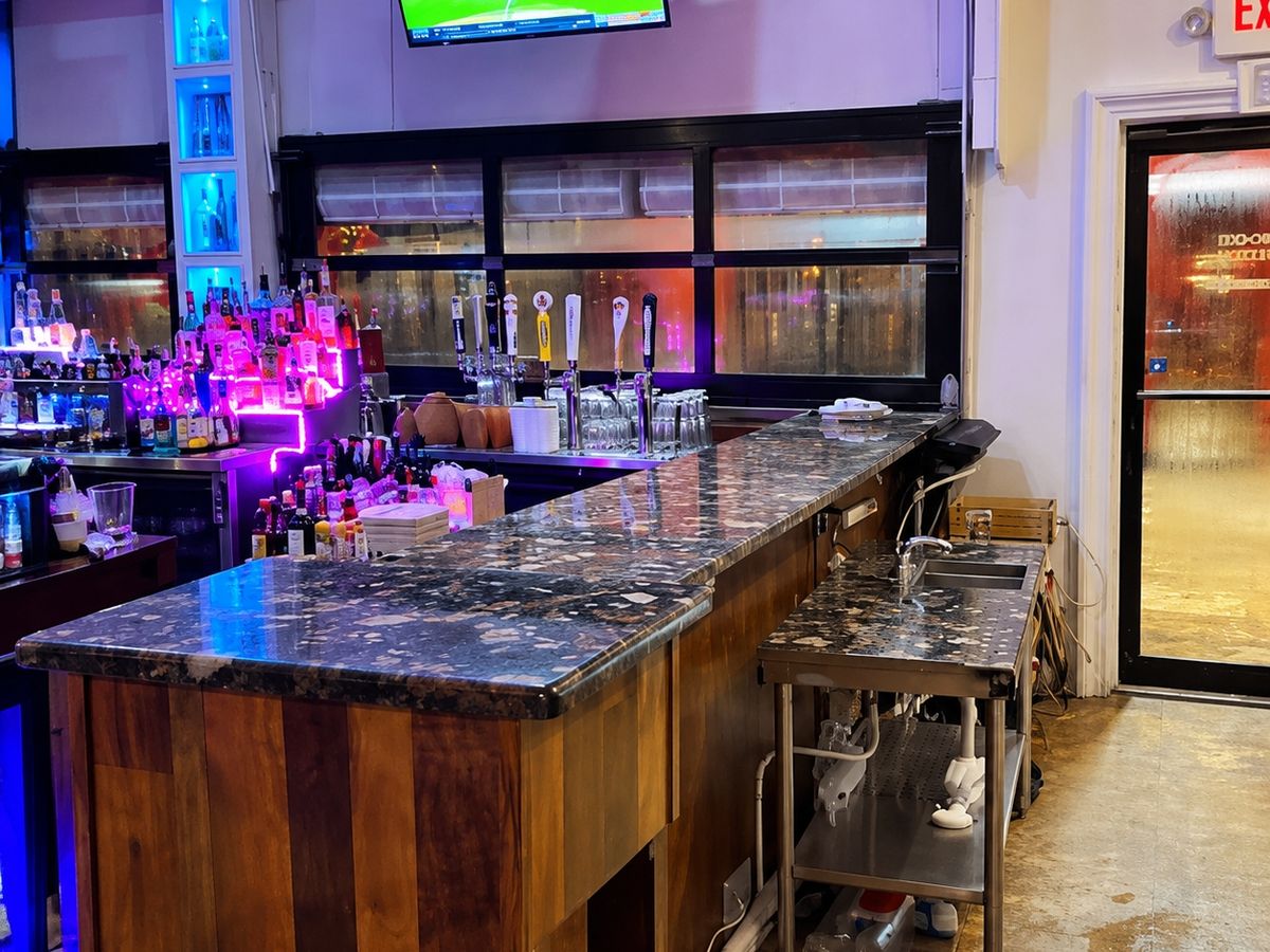 Finished restaurant bar: a long counter faced with warm wood planks under a dark polished stone top