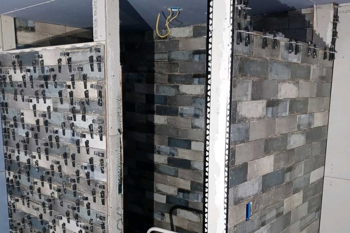 Walk-in shower being tiled in gray and blue weathered-wood-look plank tile