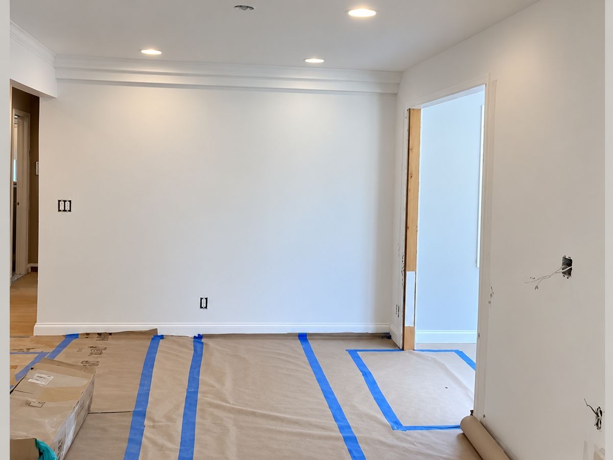 White-painted room with crown molding and recessed lights, with paper protecting the floor